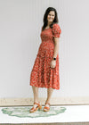 Model wearing a maroon midi dress with a cream floral pattern, bubble short sleeves and a v-neck. 