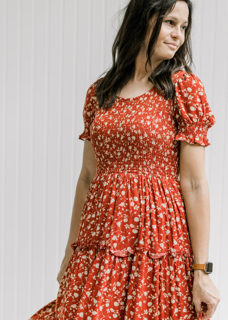 Model wearing a maroon v-neck midi with a smocked bodice, bubble short sleeves and a tiered skirt.