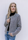 Model wearing a tweed open front jacket with a raw hemline, long sleeves and slightly cropped fit. 