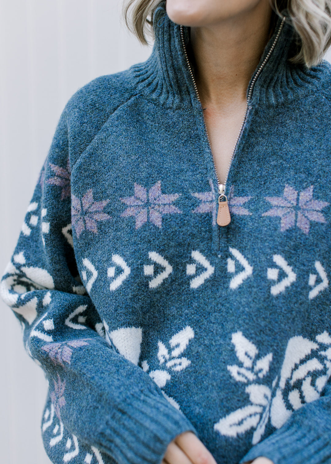 Close up of half zip sweater with mock neck in a worn navy color with off-white and indigo pattern.