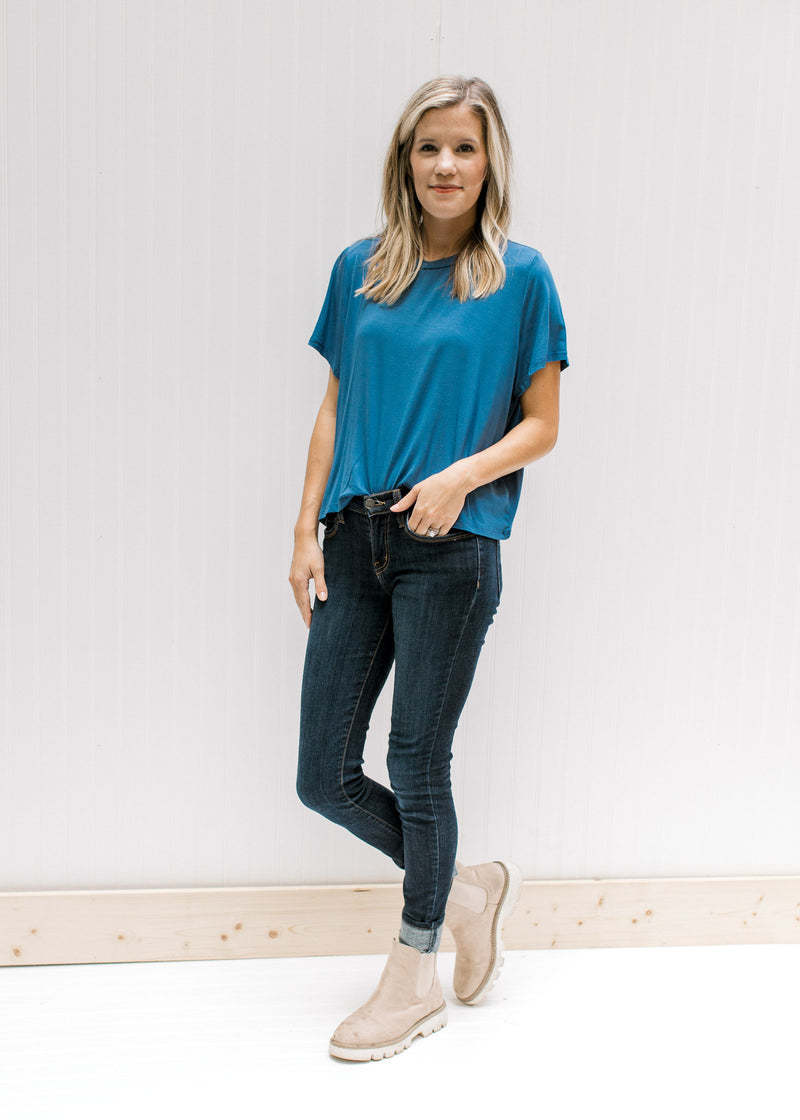 Model wearing jeans, booties and a blue short sleeve tee with a cropped fit. 