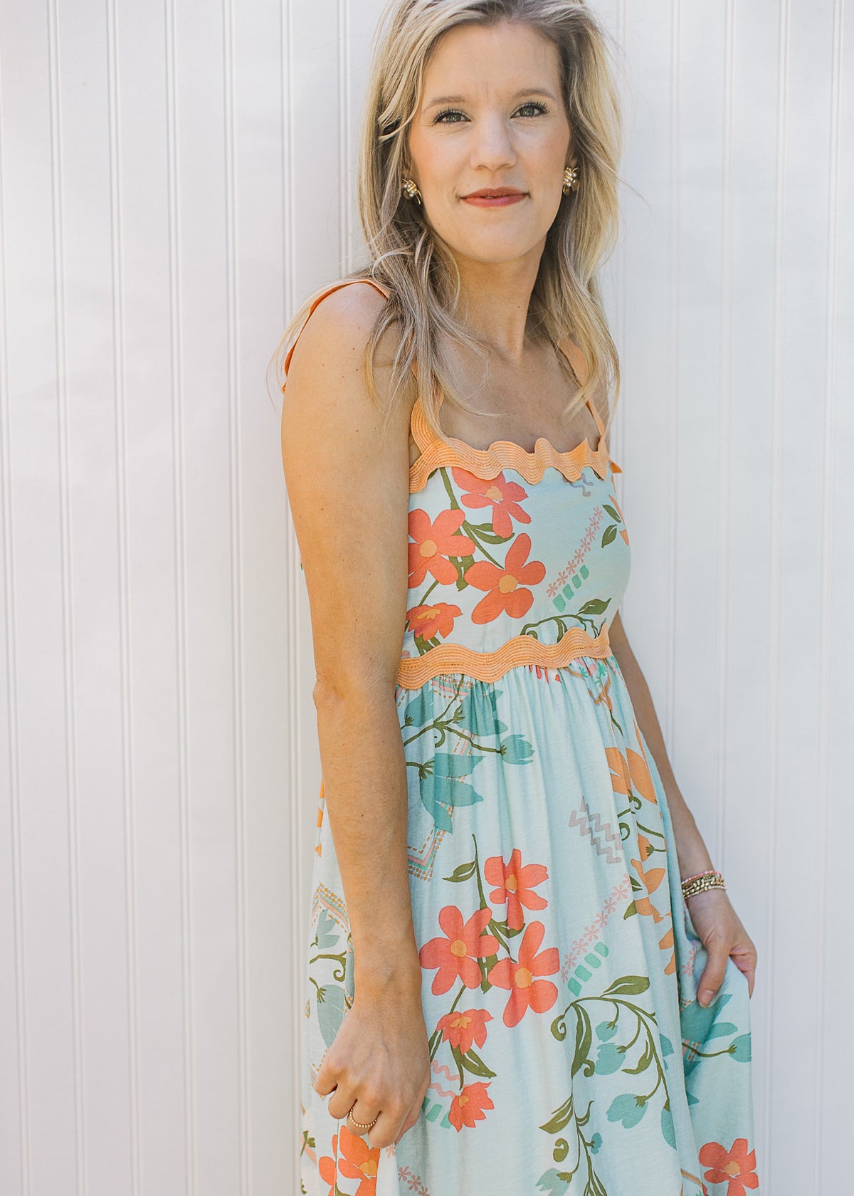 Close up of square neck and soft orange ric-rac trim on a sky blue dress with bright floral. 