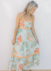 Model wearing a sky blue dress with bright floral, orange ric-rac trim and a square neckline. 