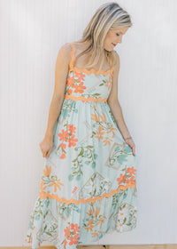 Model wearing a sky blue dress with bright floral, orange ric-rac trim and a square neckline. 