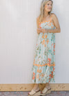 Model wearing a sky blue dress with bright floral, orange ric-rac trim and adjustable straps.