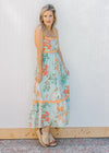 Model wearing wedges and a sky blue dress with bright floral and orange ric-rac trim.
