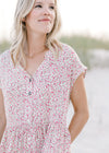 Close up of button closure on an ivory dress with a pink floral pattern and short sleeves.