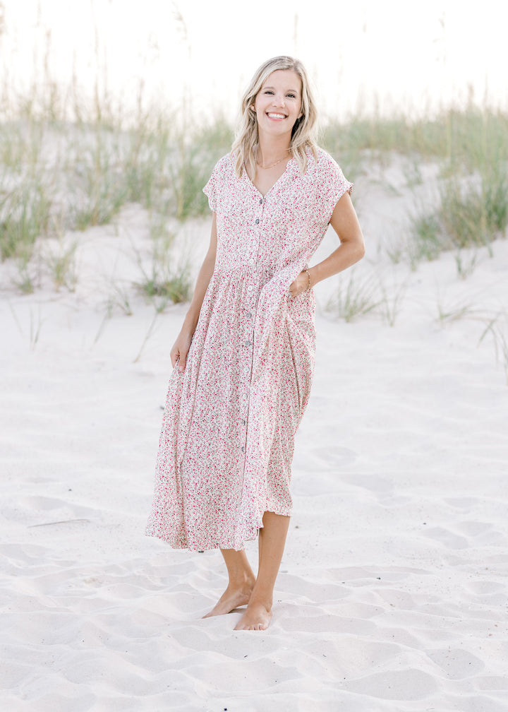 Model wearing an ivory dress with a pink floral pattern, button closure and short sleeves.