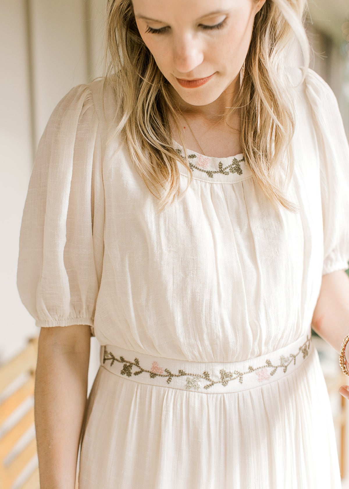 Close up of green and pink floral embroidery at the neck and waist of a short sleeve maxi.