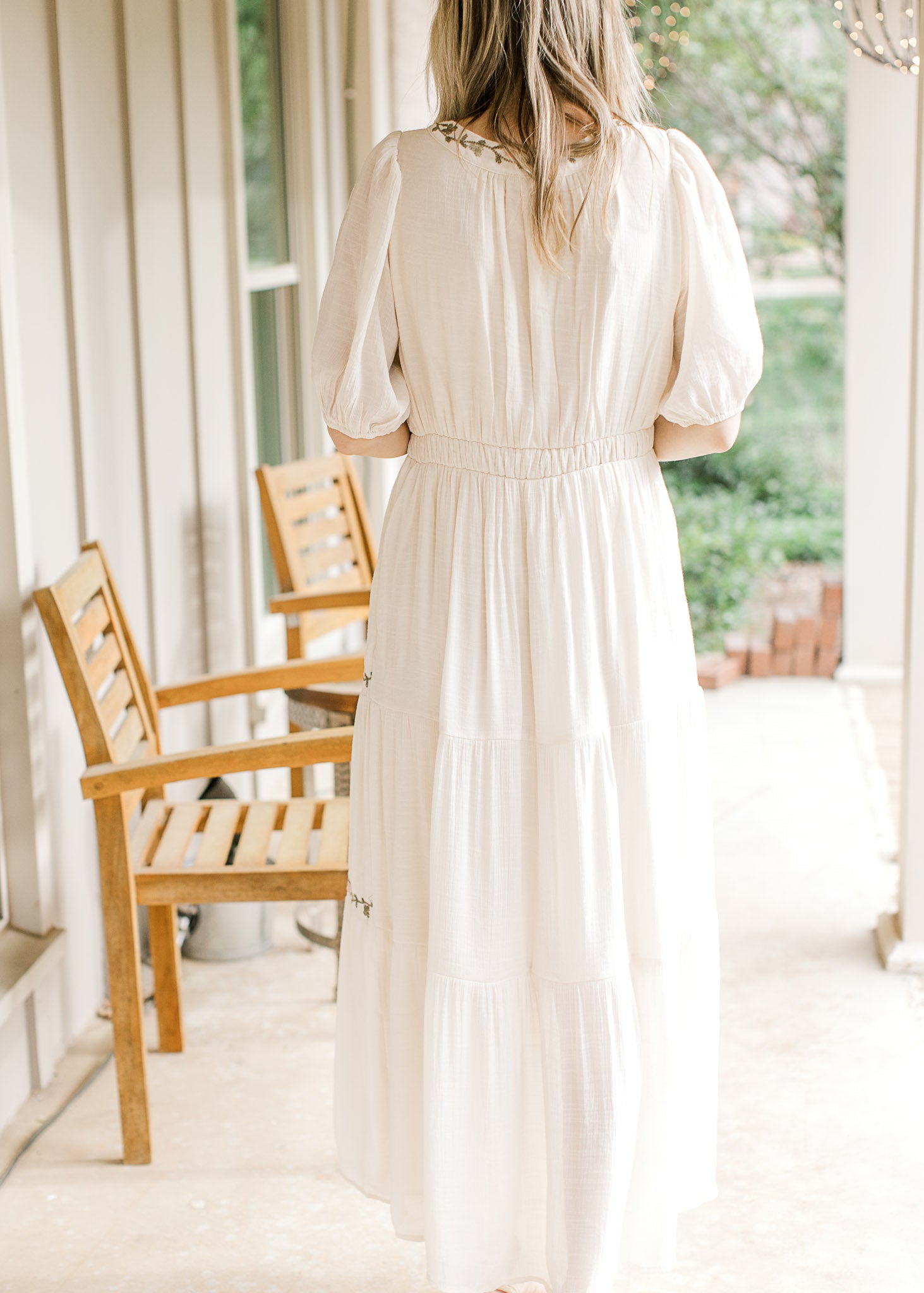 Back view of Model wearing a cream short sleeve maxi with elastic waist, tiers and short sleeves. 