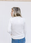 Back view of Model wearing jeans with an ivory form fitted top with a mock neck and long sleeves.