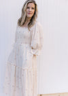 Model wearing an ivory dress with a square neckline, smocked bodice, pockets and a gauze material.