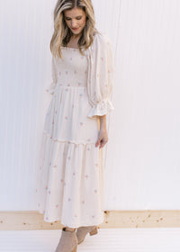 Model wearing a cream midi with pink flowers, a square neckline and 3/4 poet sleeves. 