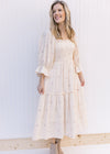 Model wearing an ivory midi with pink flowers, 3/4 poet sleeves and a gauze material. 