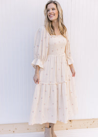 Model wearing an ivory midi with pink flowers, 3/4 poet sleeves and a gauze material. 