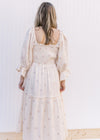 Back view of Model wearing an ivory midi with pink flowers, 3/4 poet sleeves and a gauze material.