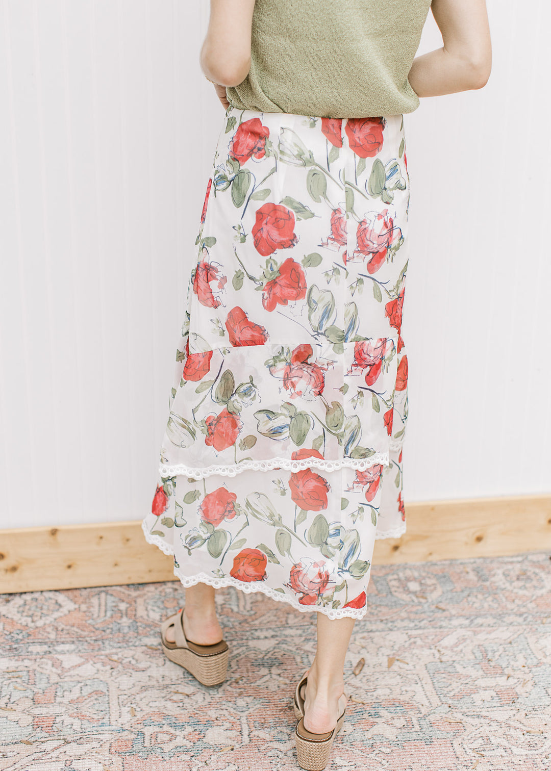 Back view of Model wearing an ivory midi with red floral, tiers with lace trim and a hidden zipper.