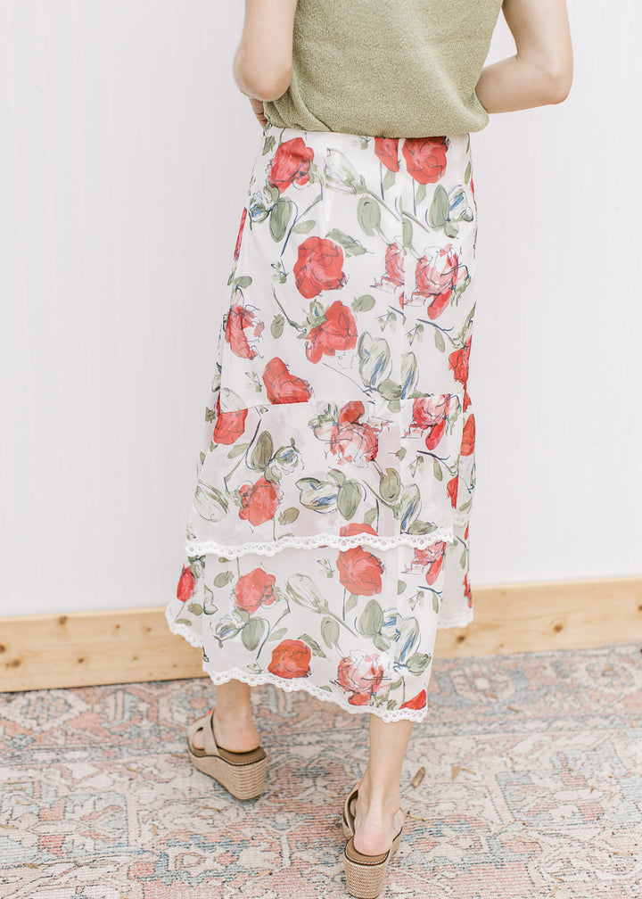 Back view of Model wearing an ivory midi with red floral, tiers with lace trim and a hidden zipper.