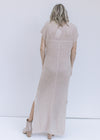 Back view of a model wearing an ivory maxi dress with a slightly sheer finish and capped sleeves. 