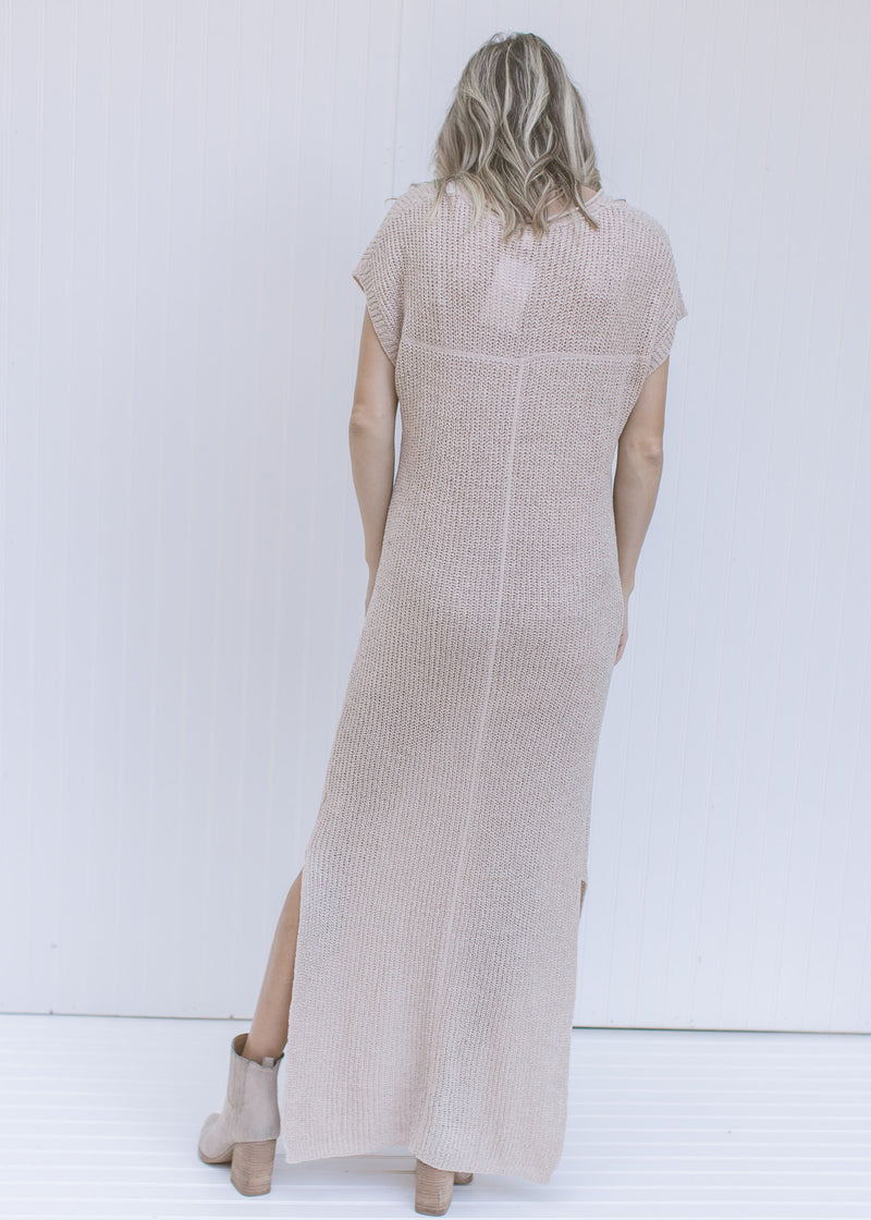 Back view of a model wearing an ivory maxi dress with a slightly sheer finish and capped sleeves. 