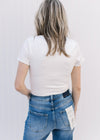 Back view of Model wearing a short sleeve ivory bodysuit with a double clasp closure.