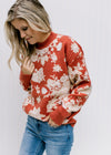 Model wearing a brick sweater with an ivory floral pattern, long sleeves and a round neck. 