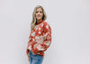 Model wearing a long sleeve brick sweater with an ivory floral pattern and a round neckline. 