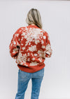 Back view of Model wearing a brick sweater with ivory floral pattern, long sleeves and round neck.