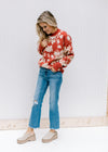 Model wearing jeans, mules and a brick sweater with an ivory floral pattern and long sleeves. 
