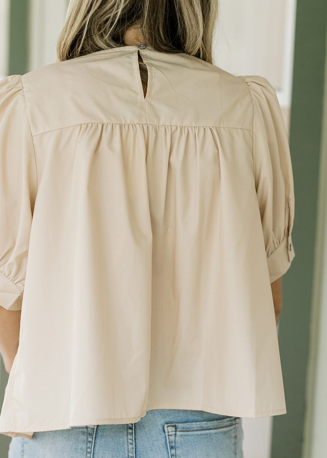 Back view of ivory blouse with bubble short sleeves, keyhole closure and light pleating. 
