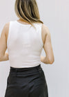 Back view of a model wearing a ribbed ivory sleeveless bodysuit with a 2 snap closure. 