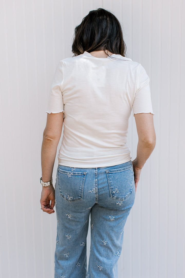Back view of Model wearing a ribbed ivory top with faux pearl button front, v-neck and short sleeves.