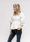 Model wearing jeans with an ivory top with a textured material, square neck and bubble 3/4 sleeves.