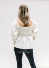 Back view of Model wearing an ivory top with a smocked bodice, square neck and bubble 3/4 sleeves.