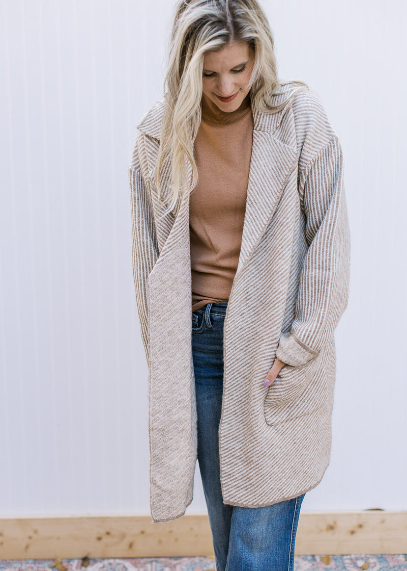 Model wearing a cream long sleeve jacket with tan stripes, a flap collar and patch pockets. 