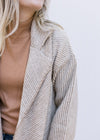 Close up of flap collar on a cream long sleeve jacket with tan stripes and patch pockets.