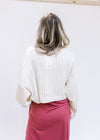 Back view of Model wearing a ribbed ivory sweater with  a cropped fit and long sleeves.