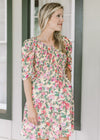 Model wearing a yellow dress with pink and green floral, a smocked bodice and short pleated sleeves.