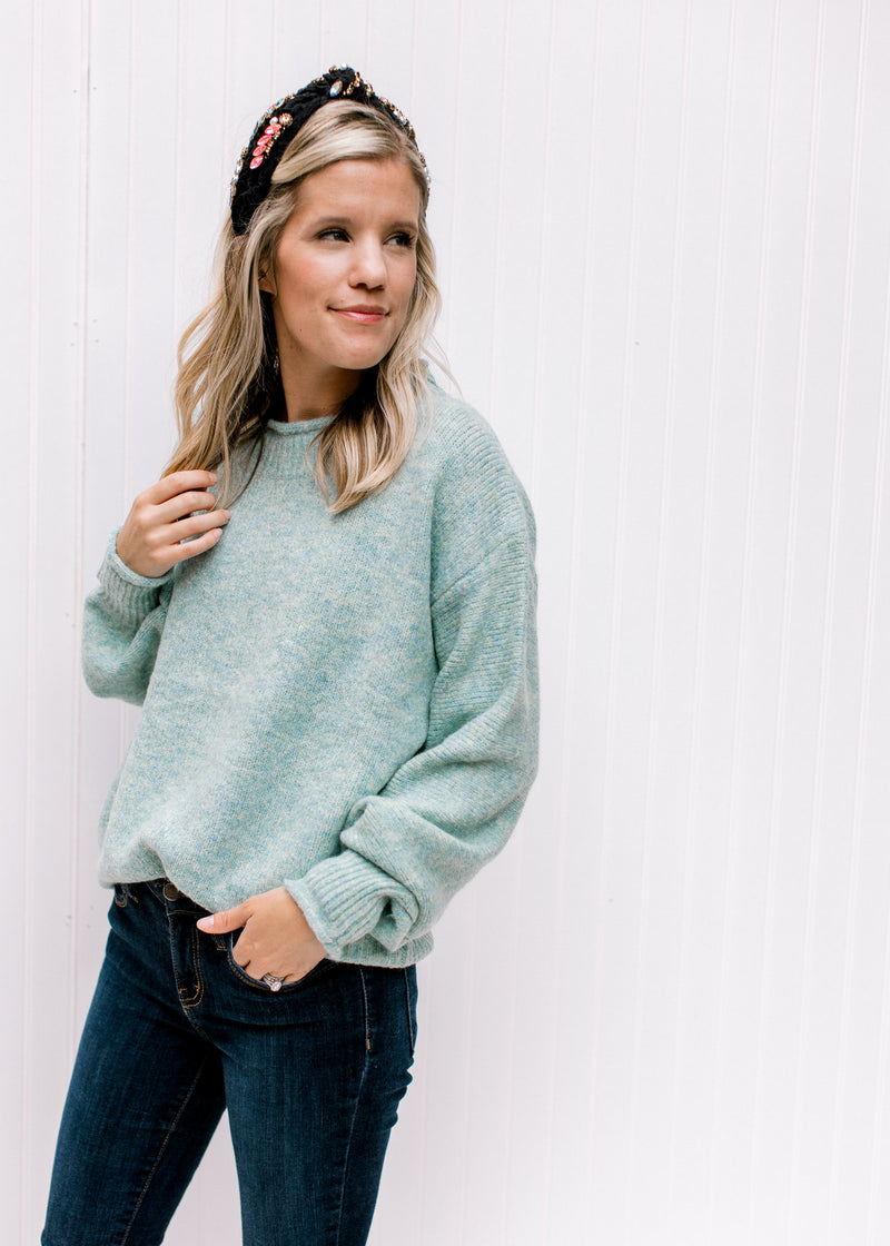 Model wearing a soft and cozy, jade knit top with long sleeves and rolled hem detail. 