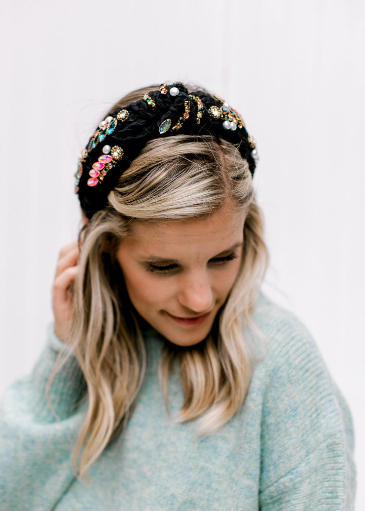 Model wearing a black headband with a jade knit top with long sleeves and rolled hem detail. 