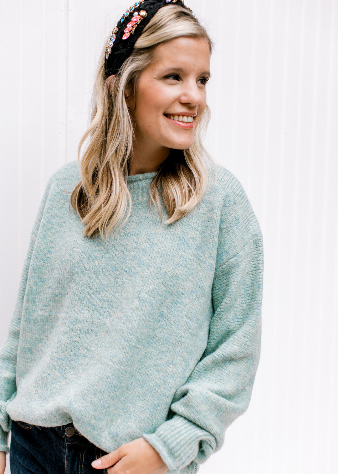 Model wearing a soft and cozy, jade knit top with long sleeves, round neck and rolled hem detail. 