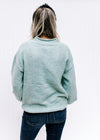 Back view of Model wearing a soft and cozy, jade knit top with long sleeves and rolled hem detail. 