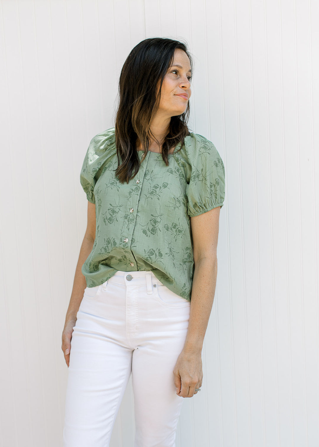 Model wearing white jeans and a sage top with floral, button front, square neck and short sleeves.
