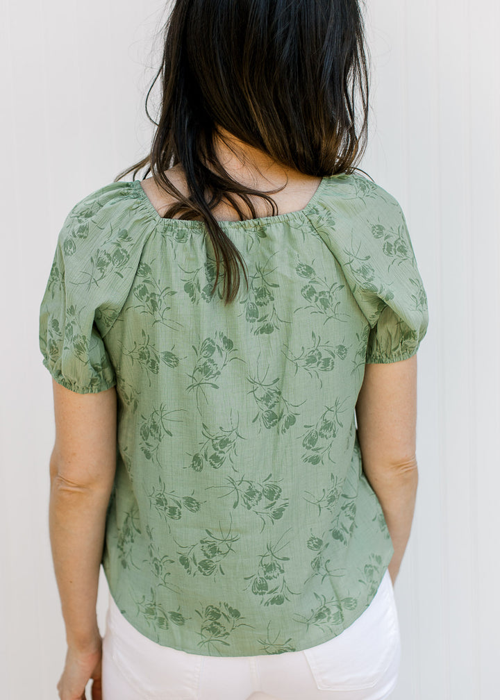 Back view of Model wearing a sage top with floral, square neck and bubble short sleeves.
