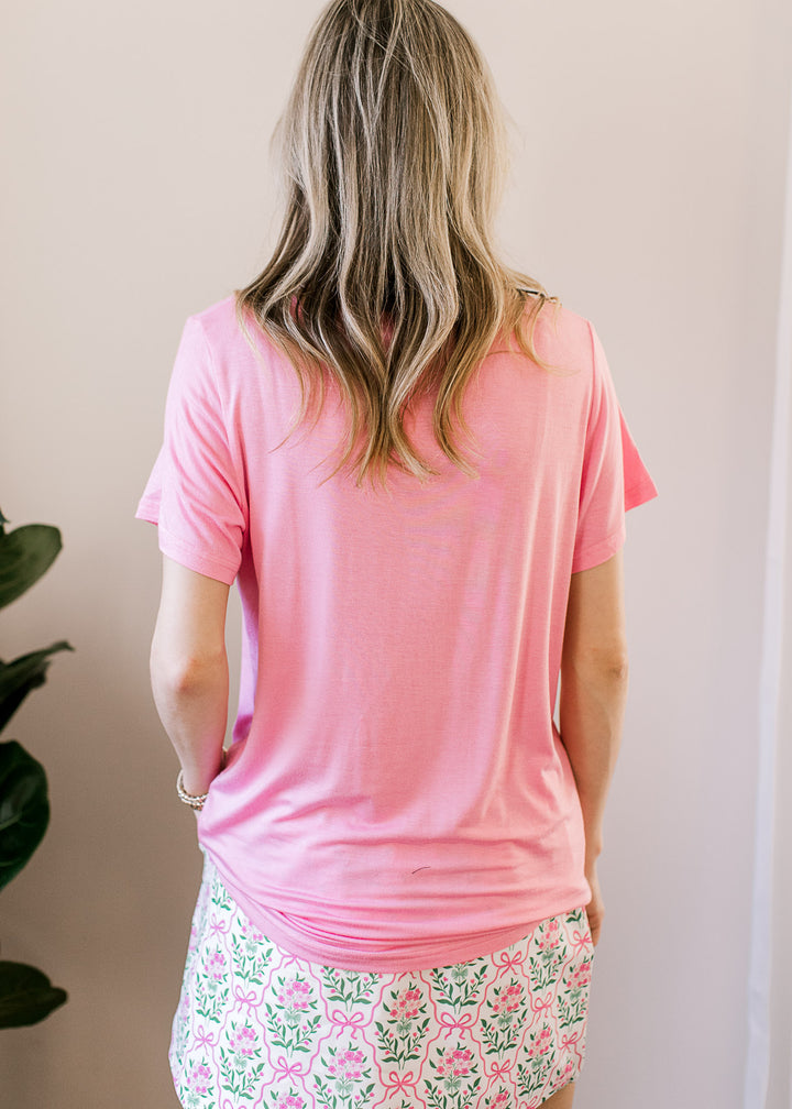 Back view of Model wearing a soft pink top with a v-neck, short sleeves and a stretchy fabric.