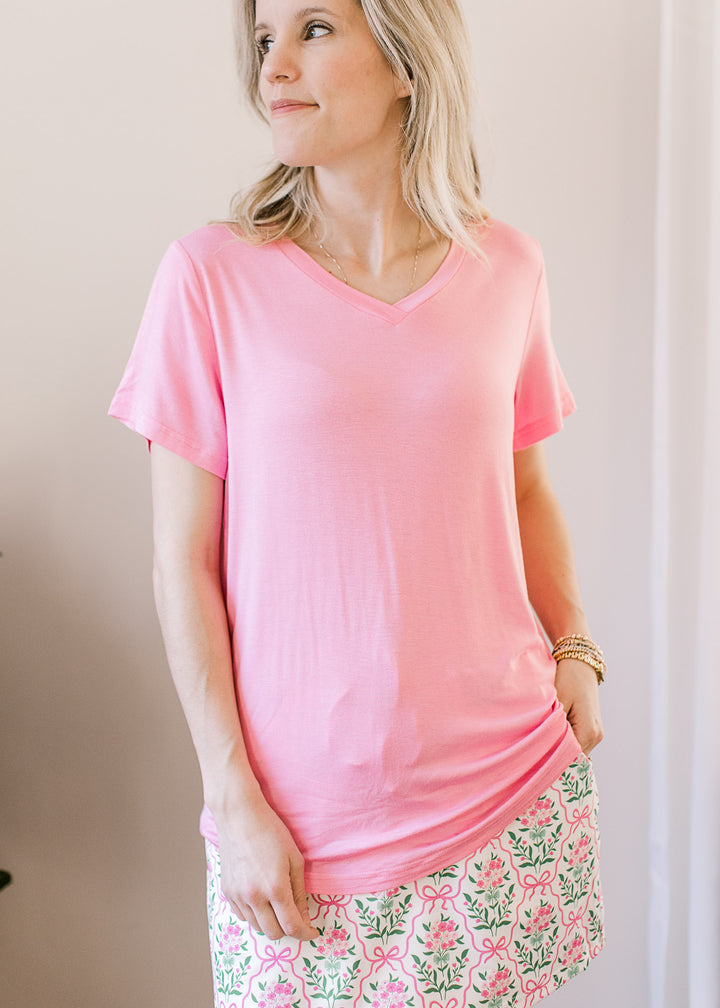 Model wearing a soft pink top with a v-neck, short sleeves and a lightweight, stretchy fabric.