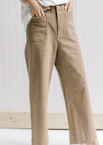 Close up of Model wearing taupe wide leg pants with hi-waisted with patch pockets.