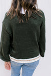 Back view of Model wearing a hunter green sweater with cream and gold at neck, hem and cuff. 