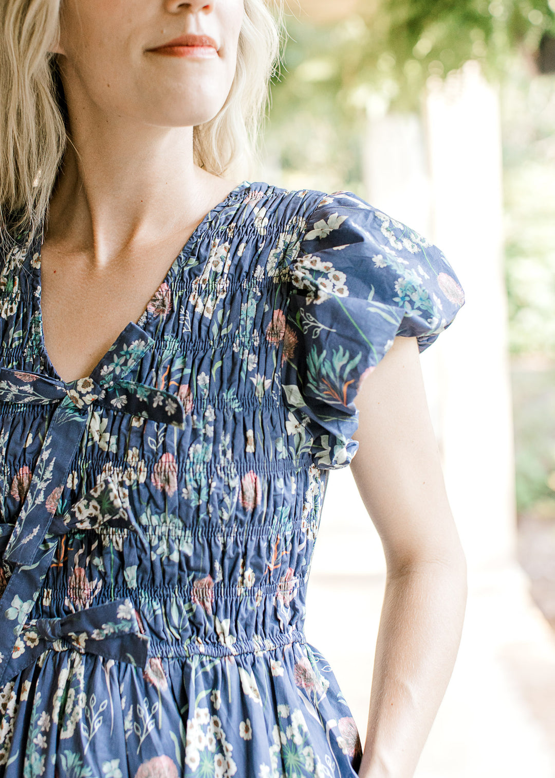 Close up of bubble short sleeves, v-neck and smocked bodice on a blue midi with floral. 