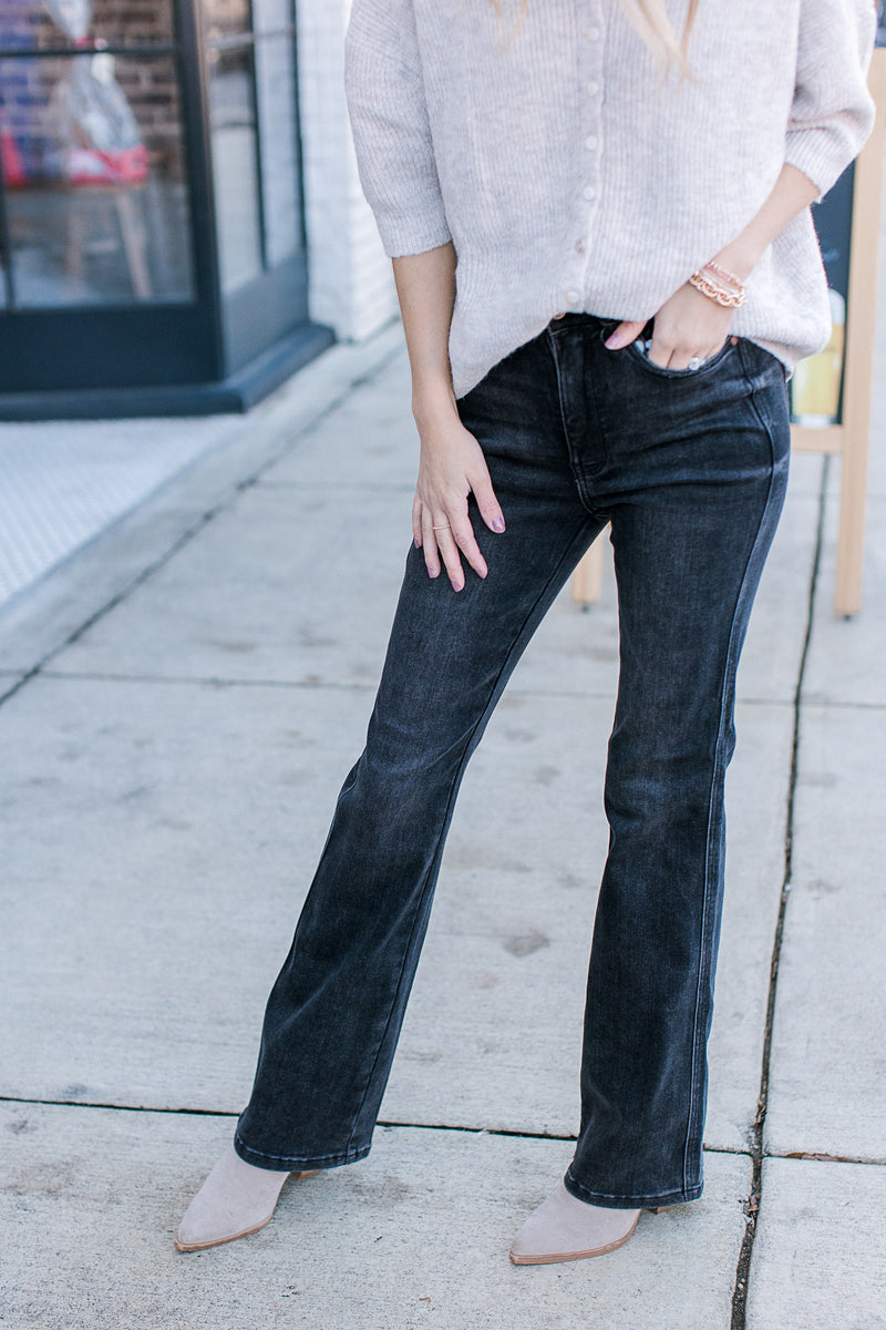 Model wearing black jeans with tummy control, high waist and bootcut fit. 